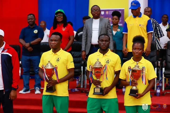 Three students holding trophy