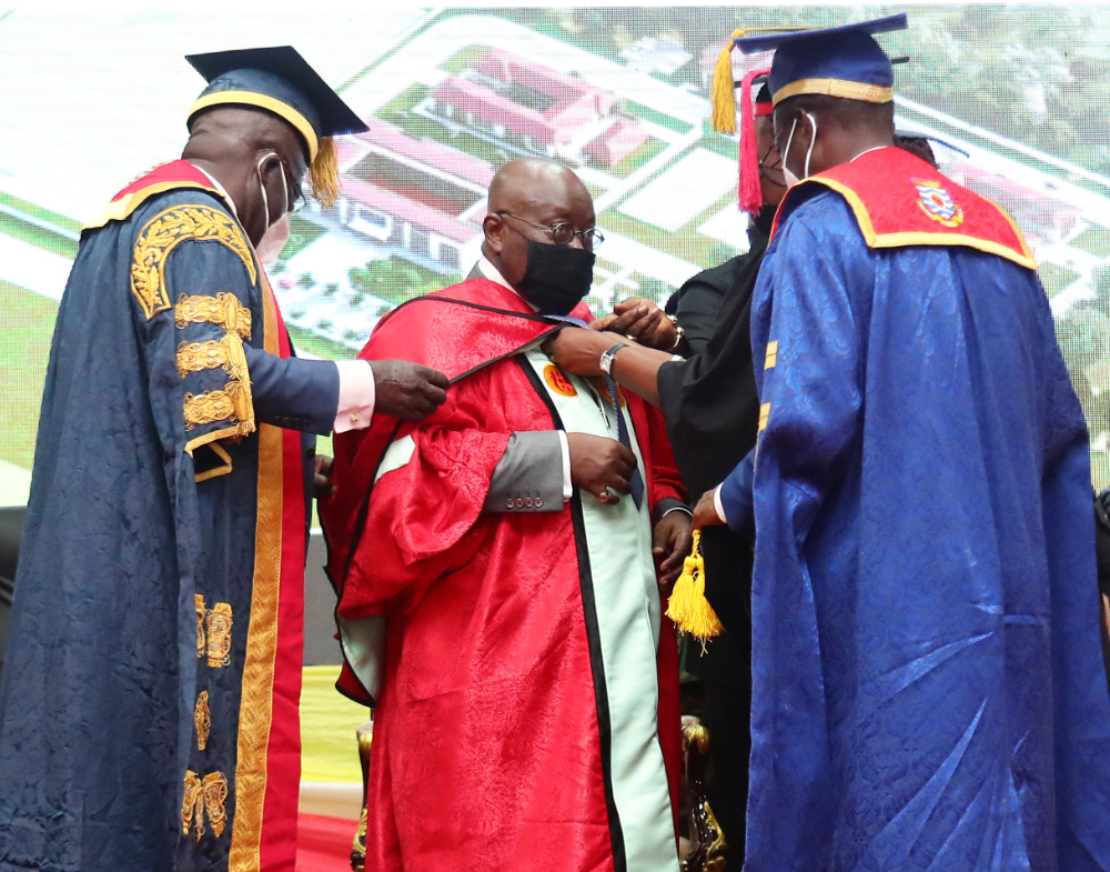 H. E. Nana Addo Dankwa Akufo-Addo, the President of the Republic being robed as Honorary Doctor by the Chancellor and Vice-Chancellor of the University of Cape Coast in 2021. Behind him is projected the building plan of 5, 500 student accommodation facili