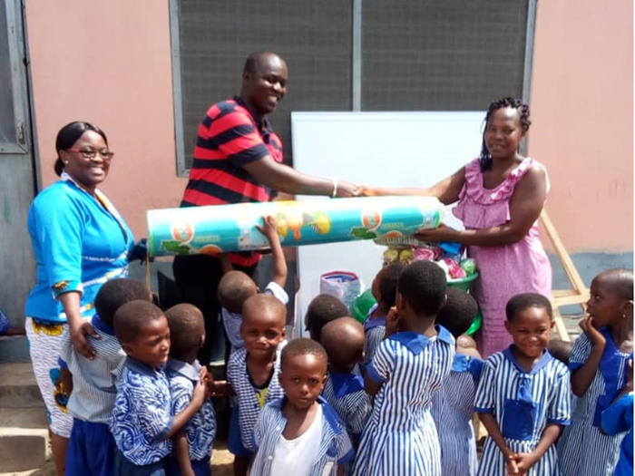 Dr. Elvis Hagan presenting the items to the Proprietoress of Hope Daycare Centre 