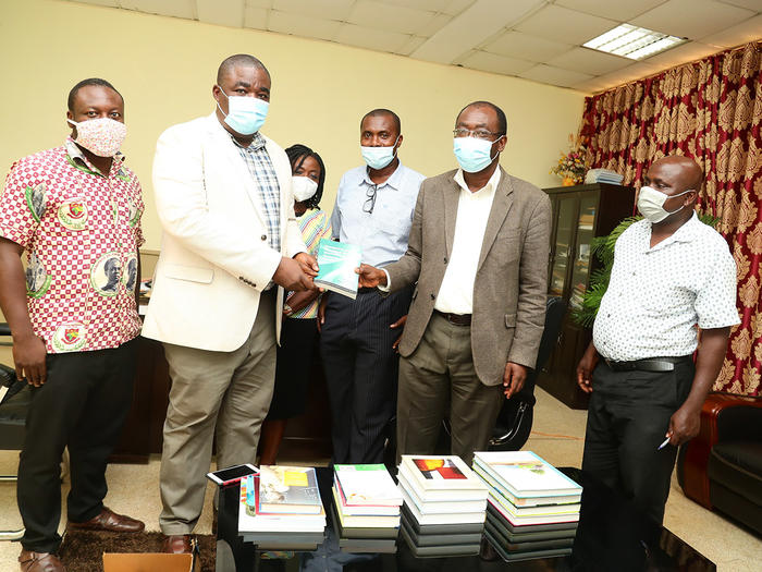 Prof. Ernest Kofi Davis handing over a books to The University Librarian, Dr. Mac Anthony Cobbla.