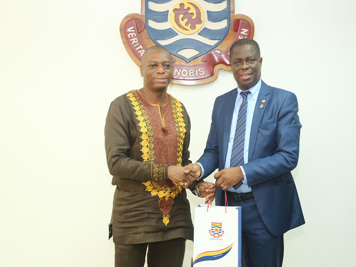 Prof. Joseph Ghartey Ampiah presenting UCC branded souvenir to Dr. Kingsley Nyarko